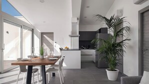 A modern kitchen with a dining area, large windows, and a potted plant. - Design Apartments D'Orlando (Capo d'Orlando)