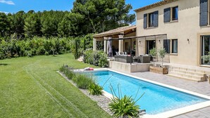 Una casa moderna con piscina, patio arredato e giardino curato.