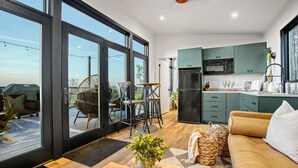 A modern kitchen with green cabinets, a black refrigerator, and a microwave. - Skyline Serenity | Hot Tub, Panoramic Views, King Bed in PA Wilds (Brookville)