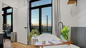 A modern bathroom with a freestanding bathtub, a small table with a book, and a potted plant. - Skyline Serenity | Hot Tub, Panoramic Views, King Bed in PA Wilds (Brookville)