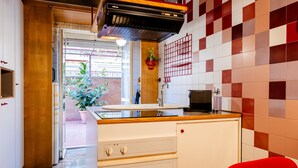 Une cuisine avec un plan de travail en bois, un évier, une cuisinière et une chaise rouge.