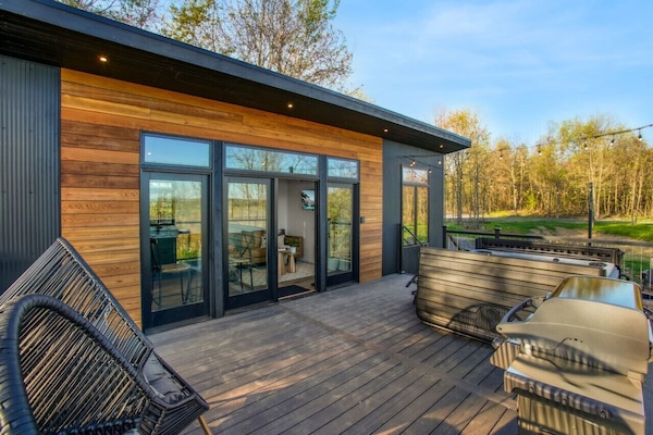 Outdoor hot tub with string lights, bbq griller and chairs in the patio