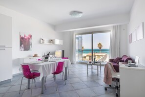 A modern hotel room with a dining area, a workspace, and a large balcony with a view of the sea. - Terraces d'Orlando (Capo d'Orlando)