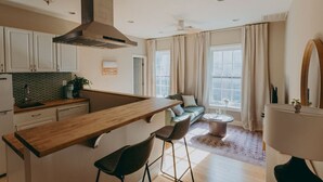 A modern kitchen with a wooden island, bar stools, and a built-in stove. - The Maisonette on Duke | King Bed, Chic, Downtown Lancaster (Lancaster)