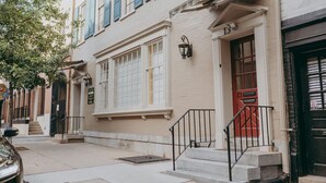 A building with a beige facade, a red door, and a black gate. - The Maisonette on Duke | King Bed, Chic, Downtown Lancaster (Lancaster)