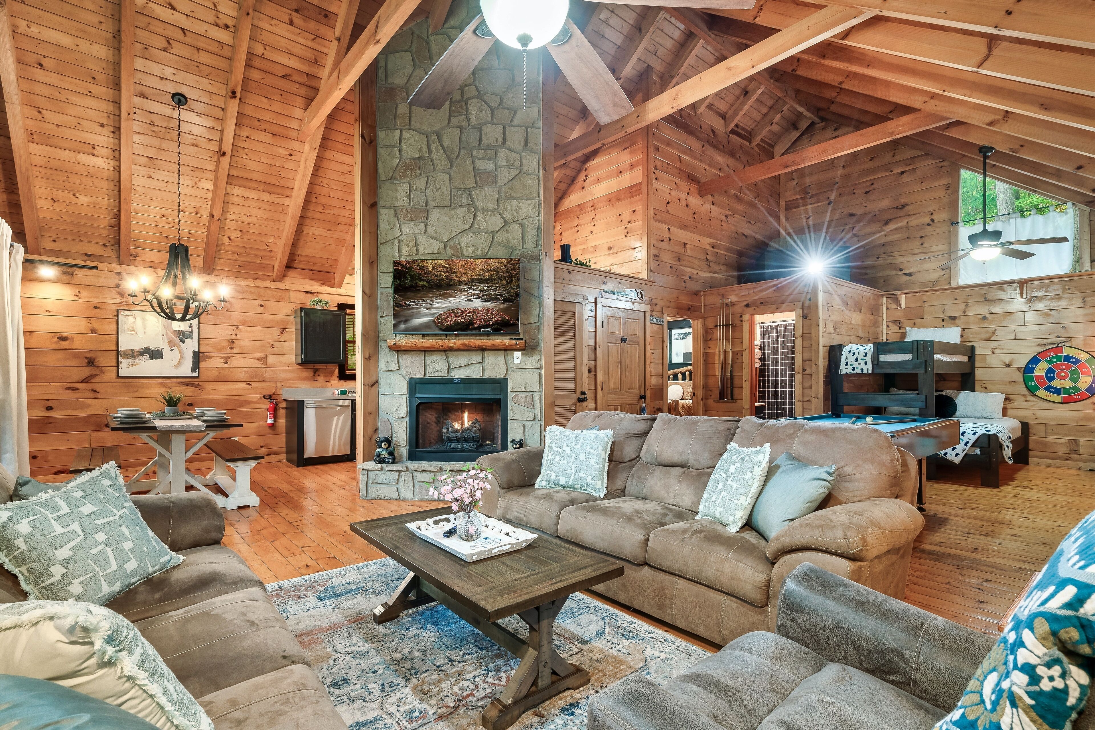 L’intérieur chaleureux d’un chalet en bois, avec une cheminée en pierre, des poutres apparentes et un coin salon confortable.