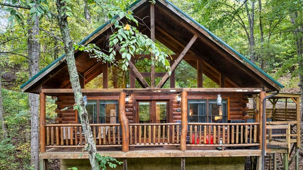 Een houten chalet met een balkon, omringd door bomen.