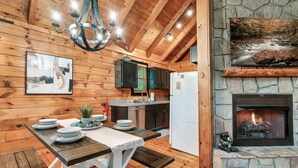 Een houten interieur met een eettafel gedekt met borden, een keuken met kasten en een stenen open haard.