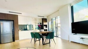 A modern kitchen with a dining area, a TV, and a large window. - Amazing 2 bedrooms condo [Street Parking, WiFi] (Zetland)