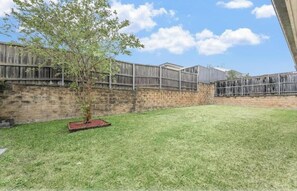 Enjoy a secure and outdoor space surrounded by a well-maintained lawn and a small tree.