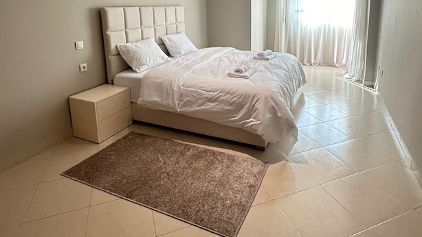 A modern bedroom with a large bed, a nightstand, and a window with curtains. - SHRTSTAYS Guesthouse (Tangier)