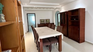 A dining area with a large table, wooden cabinets, and a statue on a shelf. - SHRTSTAYS Guesthouse (Tangier)