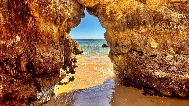 Una formación rocosa natural con la entrada de una cueva que da a una playa.