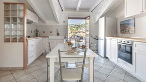 Een moderne keuken met witte kasten, een eettafel met stoelen en uitzicht op de stad.