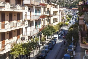 Un immeuble à plusieurs étages doté de balcons, avec des voitures garées et un passage piéton.