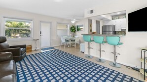 Ein modernes Wohnzimmer mit einem gemusterten Teppich, einer Couch und einem Essbereich mit Tisch und Stühlen.