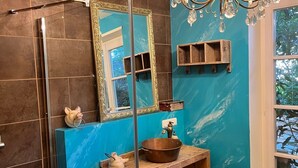 A bathroom with a large mirror, a chandelier, a sink with a copper basin, and a shower area. - Glückliche Kuh-Villa (Kempten)