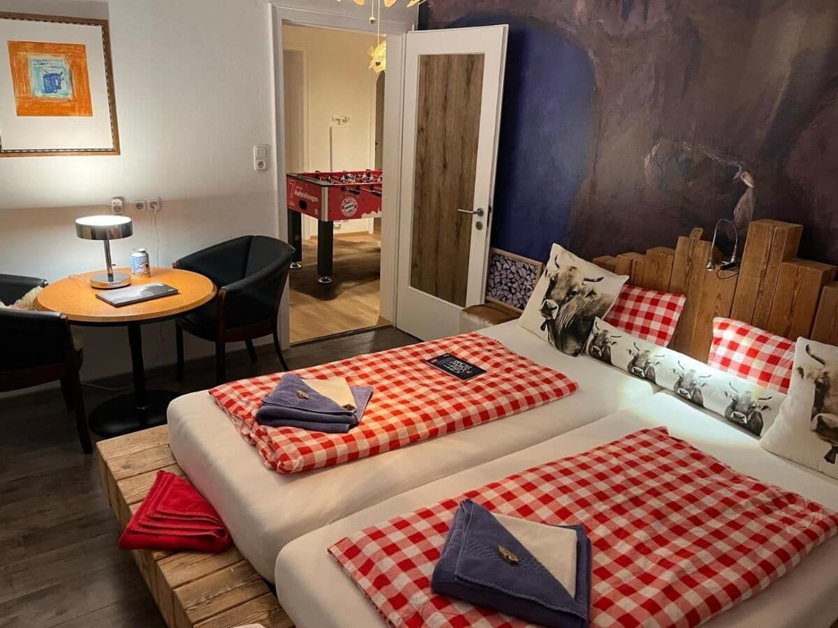 Una habitación acogedora con dos camas, una mesita y una mesa de futbolín.