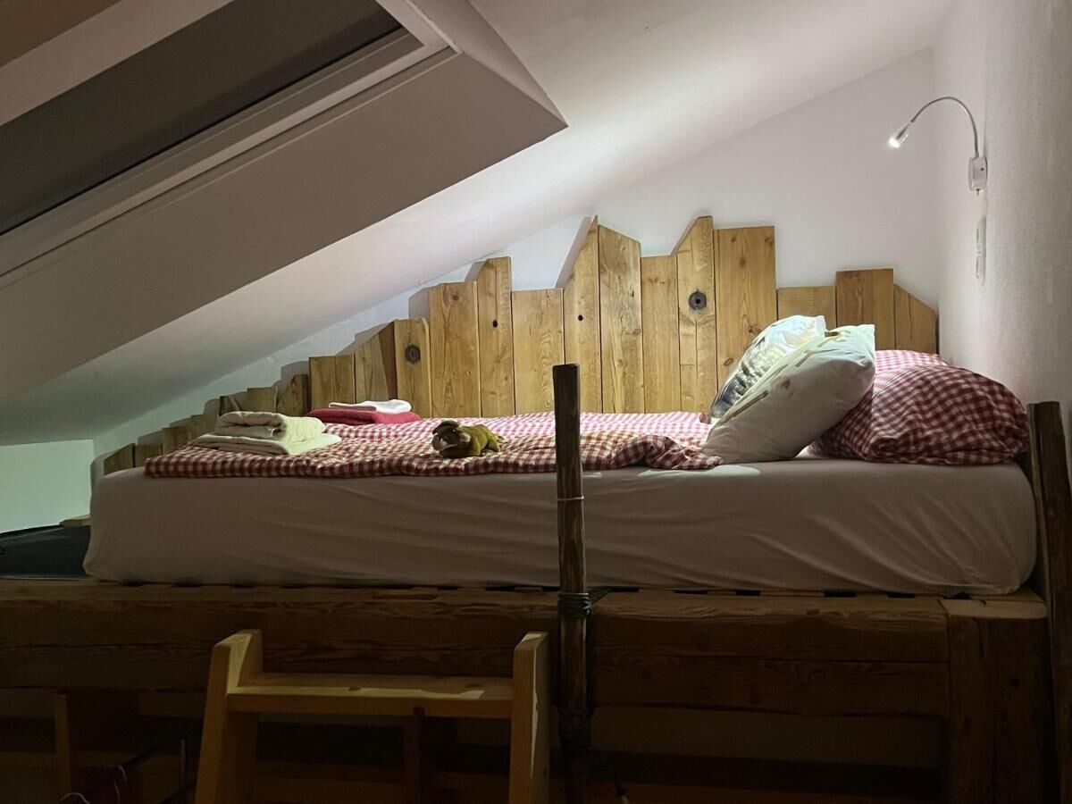 A single bed with a wooden headboard, a bedside lamp, and a small table.