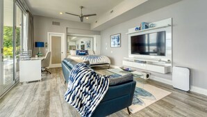 A modern living room with a sofa, TV, and a glass coffee table.
