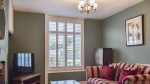 A living room with a television, a sofa, a coffee table, and a window with blinds. - 2 bedroom accommodation in Sinnington near Pickering (Sinnington near Pickering)