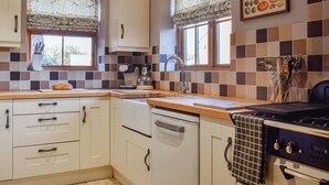 A kitchen with white cabinets, a dishwasher, a stove, and a window with a decorative valance. - 2 bedroom accommodation in Sinnington near Pickering (Sinnington near Pickering)