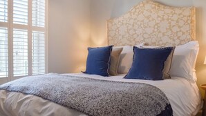 A neatly made bed with a patterned headboard, a blue and white throw blanket, and several pillows in blue and beige. - 2 bedroom accommodation in Sinnington near Pickering (Sinnington near Pickering)