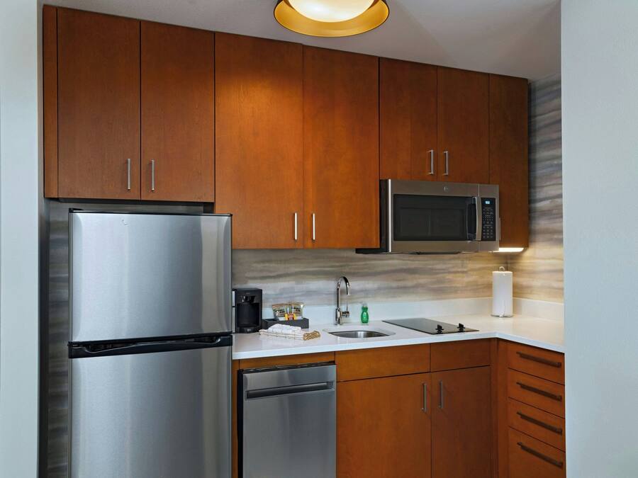 A modern kitchen with stainless steel appliances, wooden cabinets, and a marble backsplash.