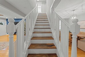 Un escalier avec des rampes blanches et des marches en bois menant à un palier situé au deuxième étage.