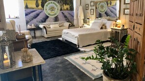 Une chambre à coucher comprenant un lit, une table de chevet, une commode, un miroir et une grande fenêtre.