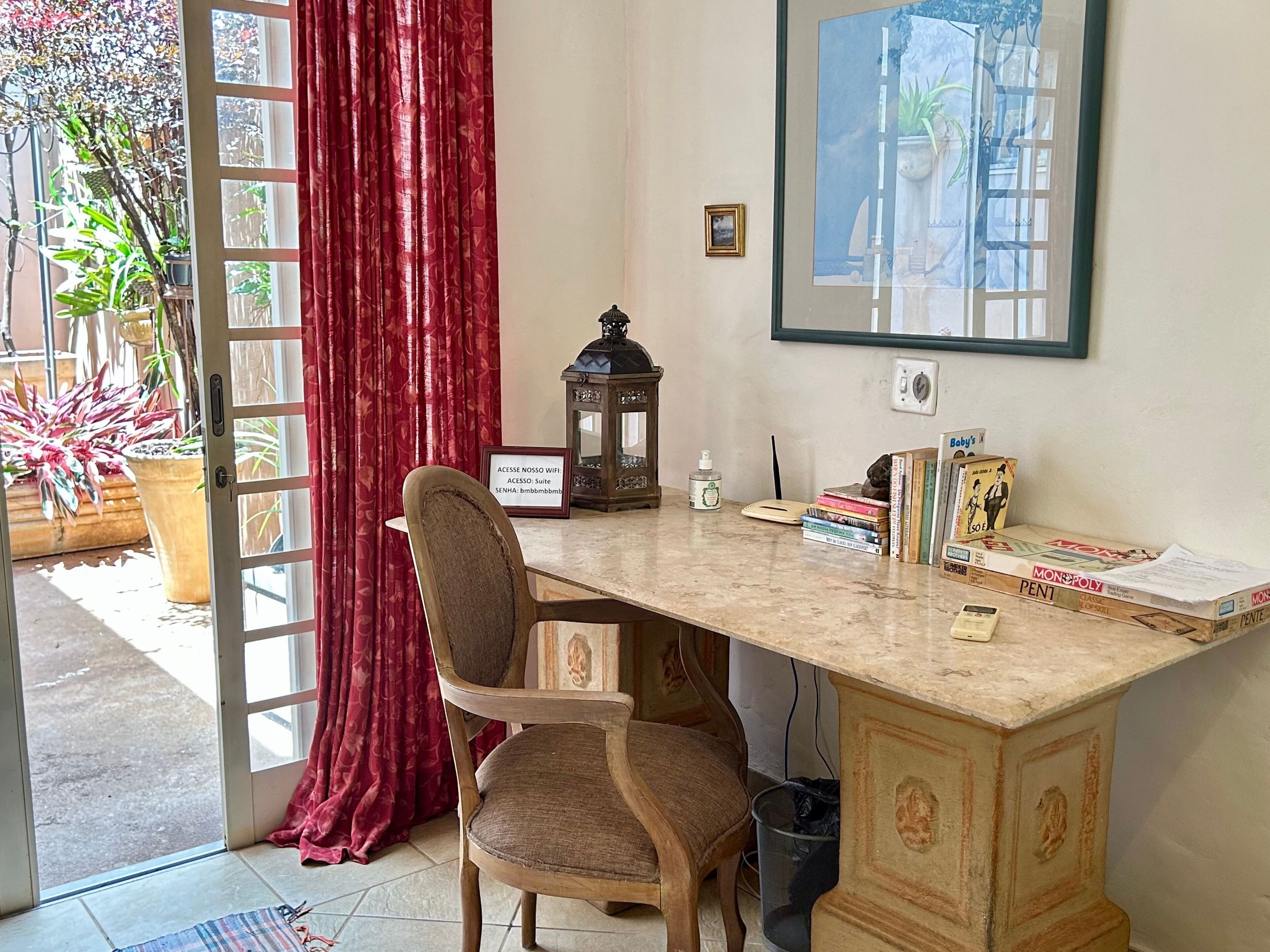 A room with a wooden desk, a chair, a framed picture on the wall, a potted plant, and a sign indicating WiFi access.