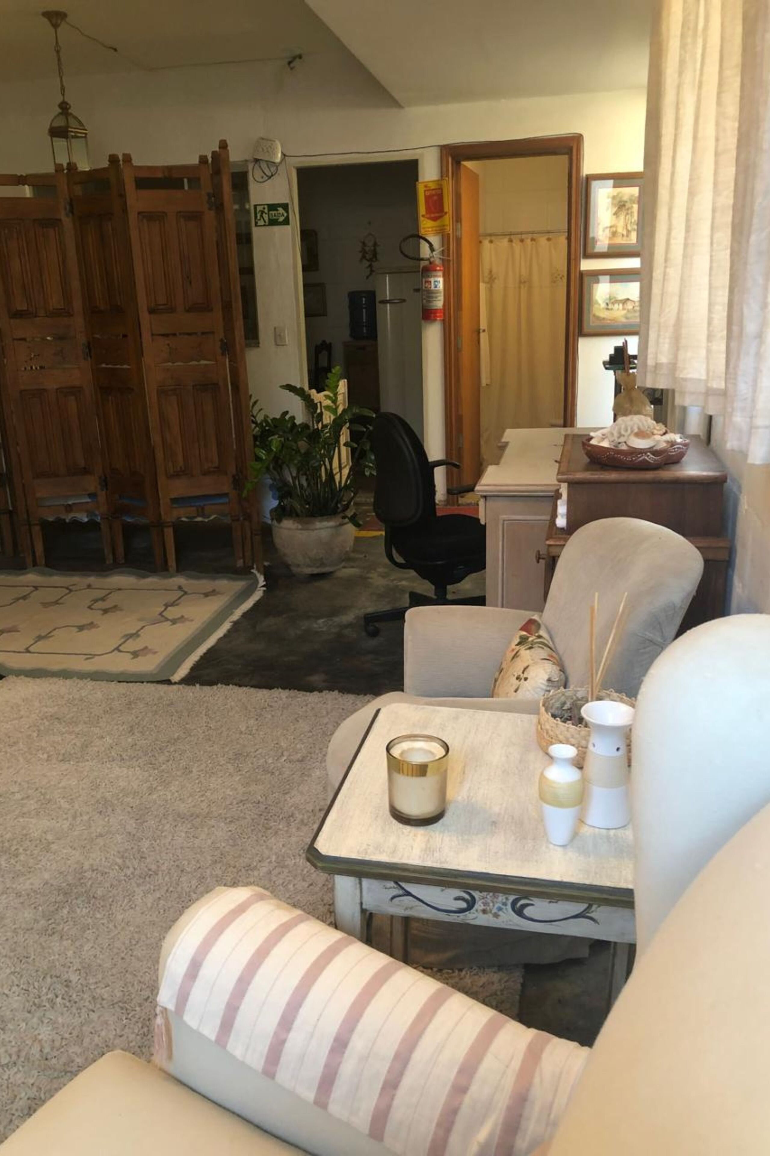 Un salon chaleureux avec un canapé, une petite table ornée de bougies, une plante en pot et une porte en bois.