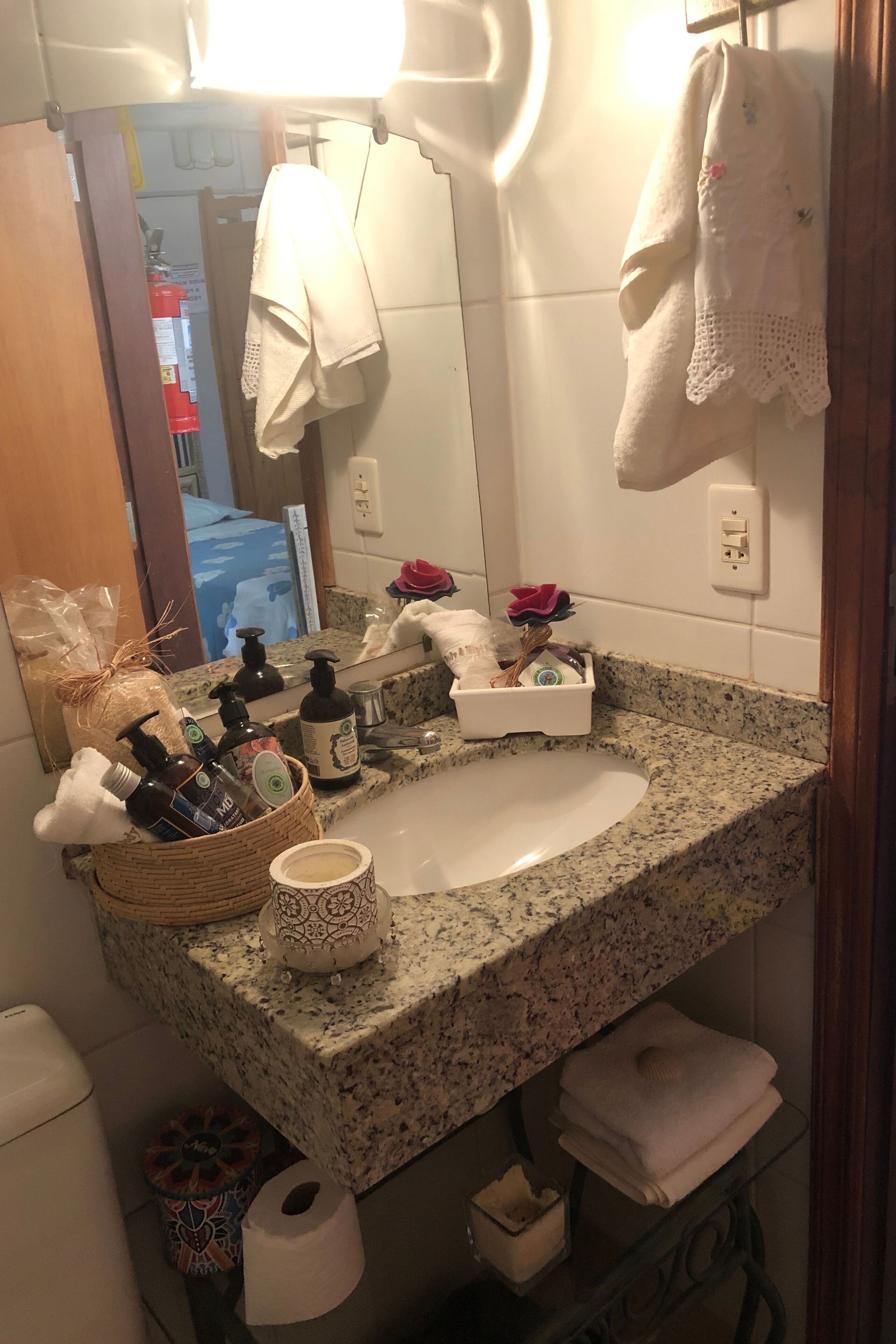 A bathroom with a granite sink, a mirror, a towel rack, and toiletries.