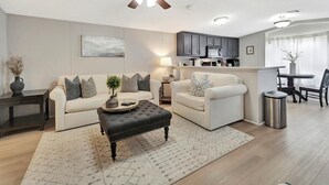Een moderne woonkamer met een bank, een poef en een plafondventilator.
