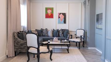 Uma sala de estar moderna com um sofá, duas poltronas, uma mesa de centro e obras de arte nas paredes.