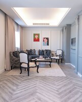 Uma sala de estar moderna com um sofá, duas poltronas, uma mesa de centro e obras de arte nas paredes.