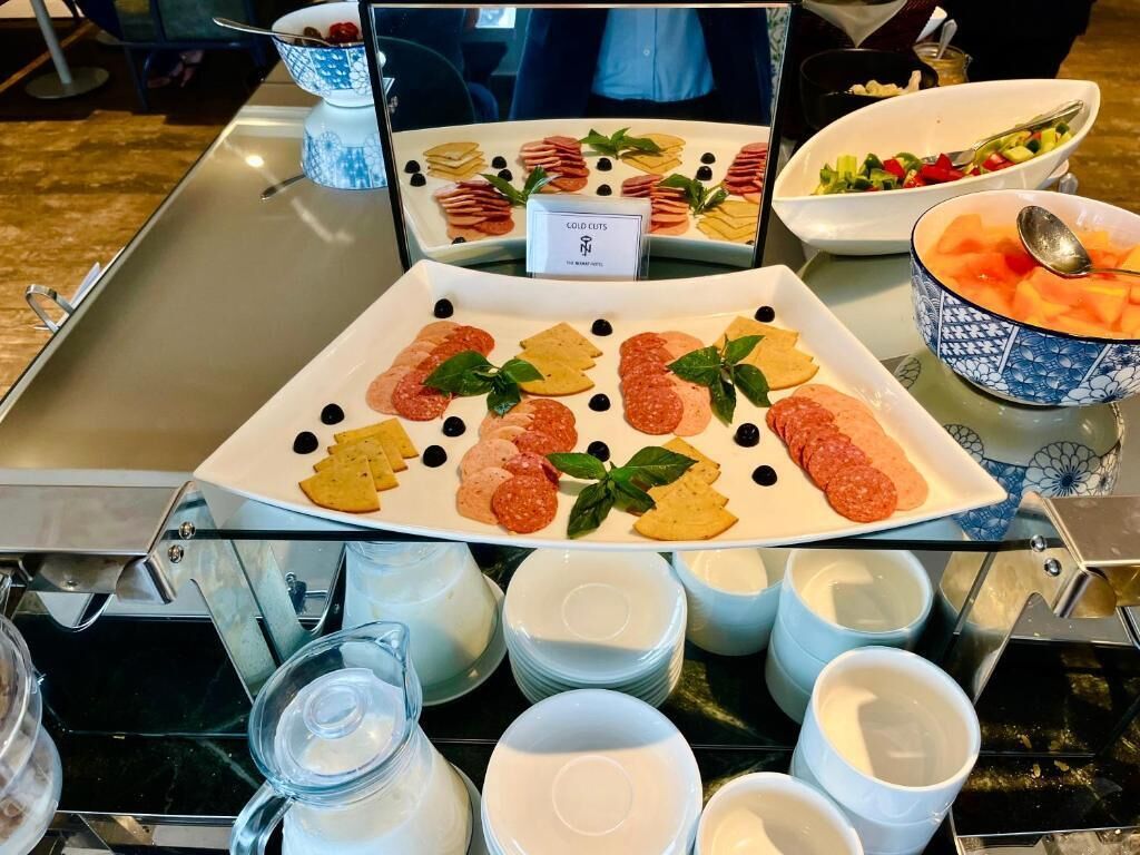 Een buffettafel met vleeswaren, kaas en olijven. Ook staan er schalen met fruit en een waterkan.