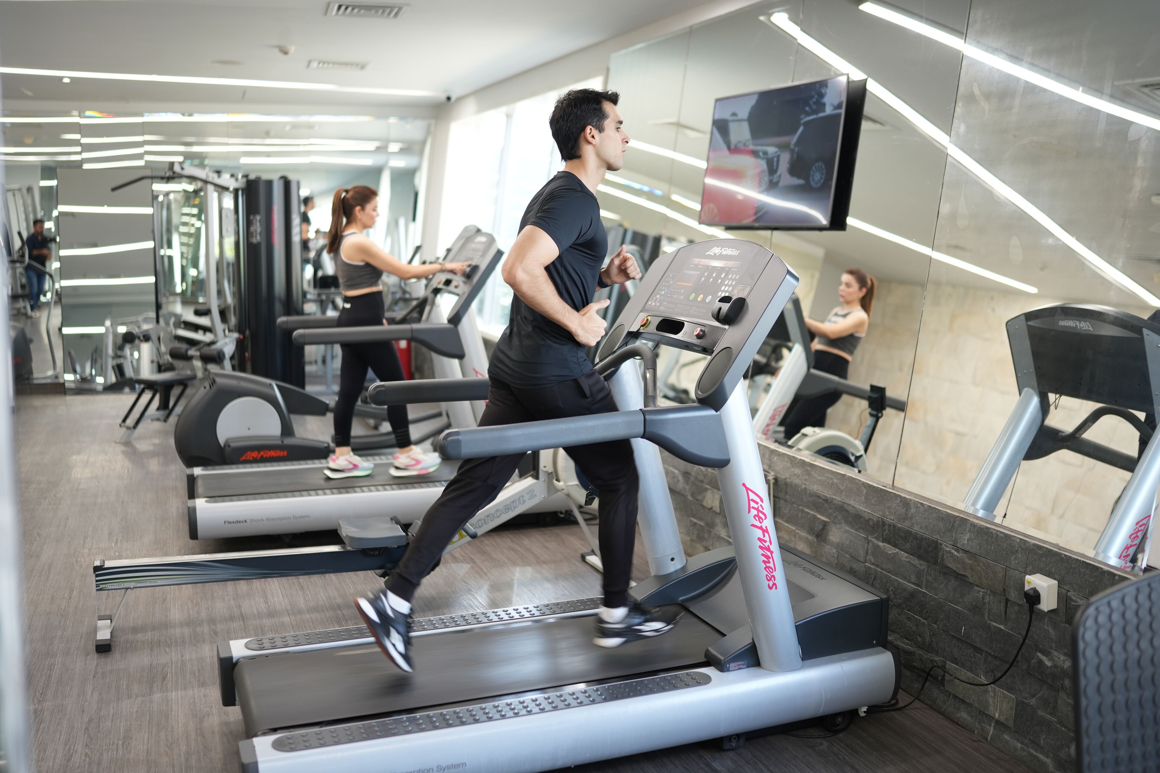 Un gimnasio con cintas de correr, espejos y equipo de ejercicio.