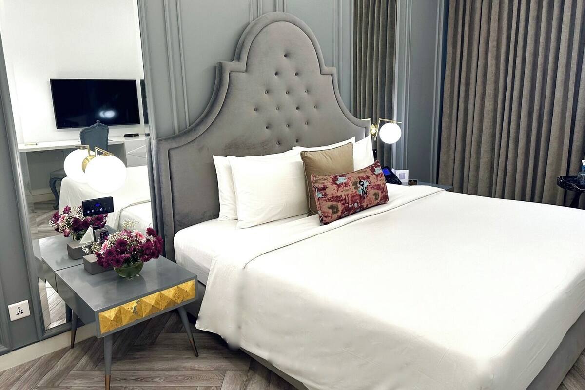 Een hotelkamer met een groot bed, een nachtkastje met een lamp, een televisie en een bloemstuk.
