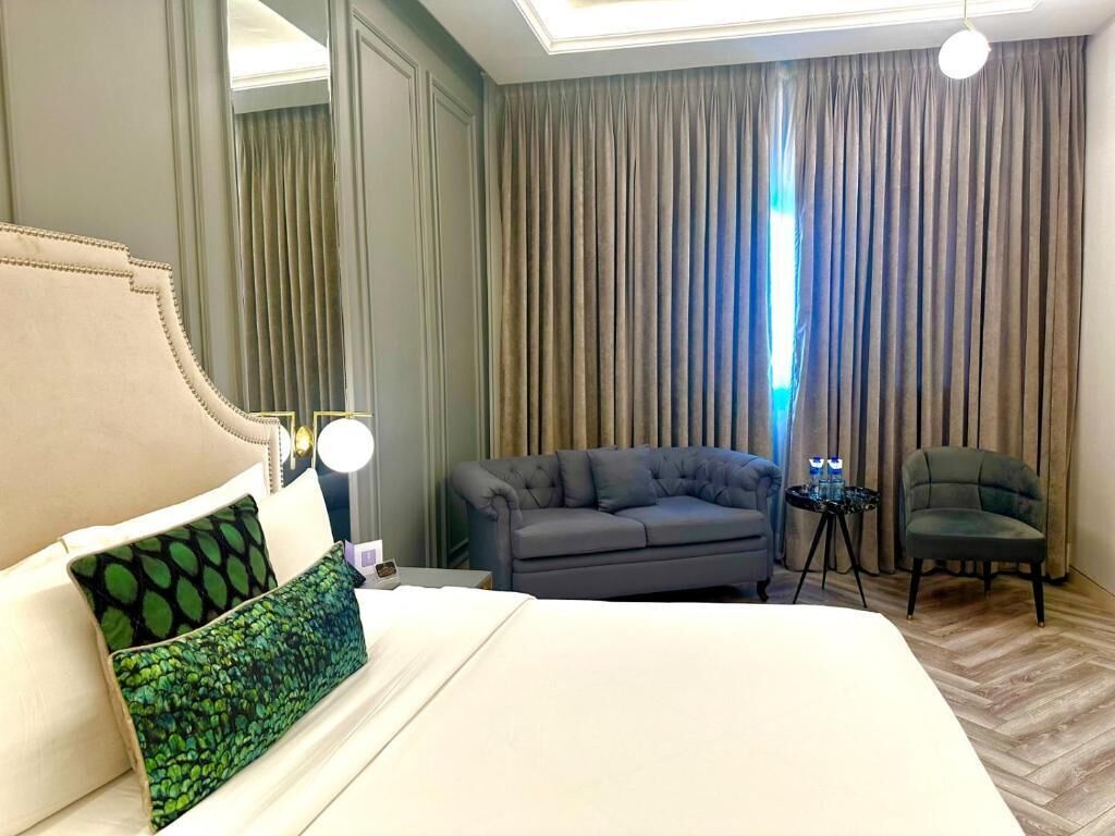 Une chambre d’hôtel avec un grand lit, un canapé gris, une petite table avec une lampe et une chaise.