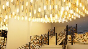 Un escalier orné de rampes en métal ouvragé et d’une série de luminaires suspendus.