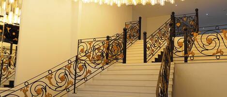 Una escalera con barandillas de metal decoradas y varios apliques colgantes.