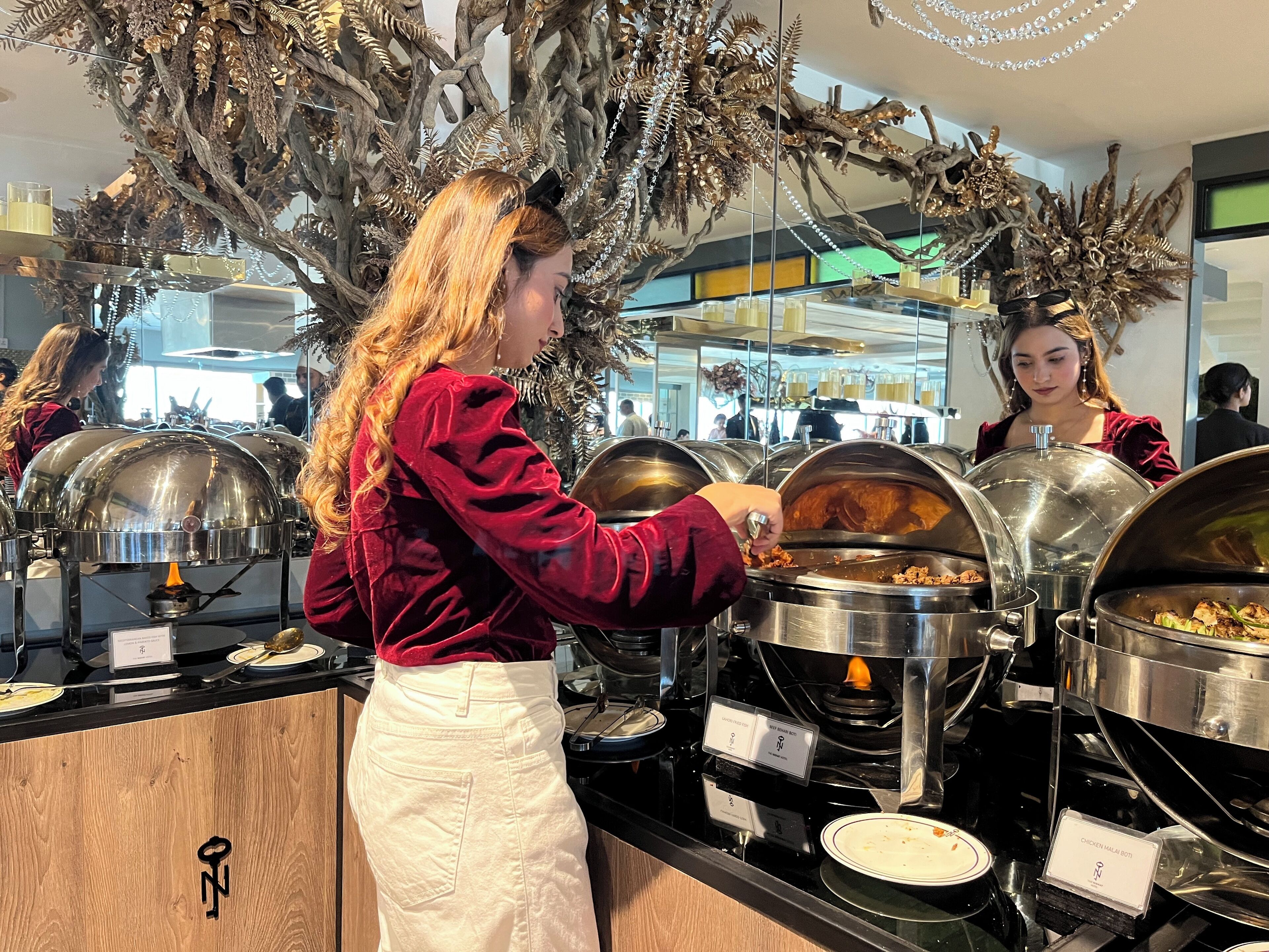 En buffetopstilling med flere serveringsstationer, herunder en station med kylling Malai Boti.