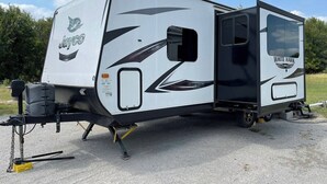 A white RV with black accents, featuring a logo and the name 'White Hawk' on the side.