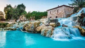 Un edificio in pietra con una piccola cascata e una piscina.