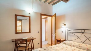 A bedroom with a bed, a desk with a chair, a mirror, and a nightstand with a lamp. - Relais il Ciliegio (Sorano)