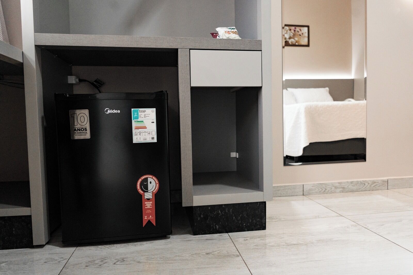 A compact minibar with a black refrigerator, a 10-year warranty sticker, and a red energy efficiency badge.