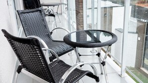 A balcony with two wicker chairs and a glass table. - MD Recanto Iguaçu (Foz do Iguacu)