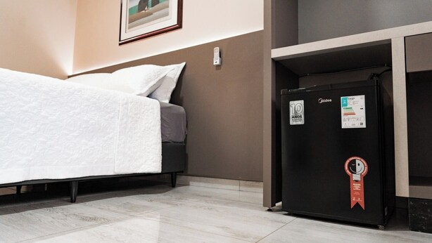 A hotel room with a bed, a black refrigerator, and a framed picture on the wall. - MD Recanto Iguaçu (Foz do Iguacu)
