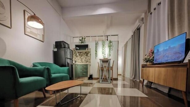 Un salon moderne avec un canapé vert, une table basse en bois et un téléviseur posé sur un meuble en bois.
